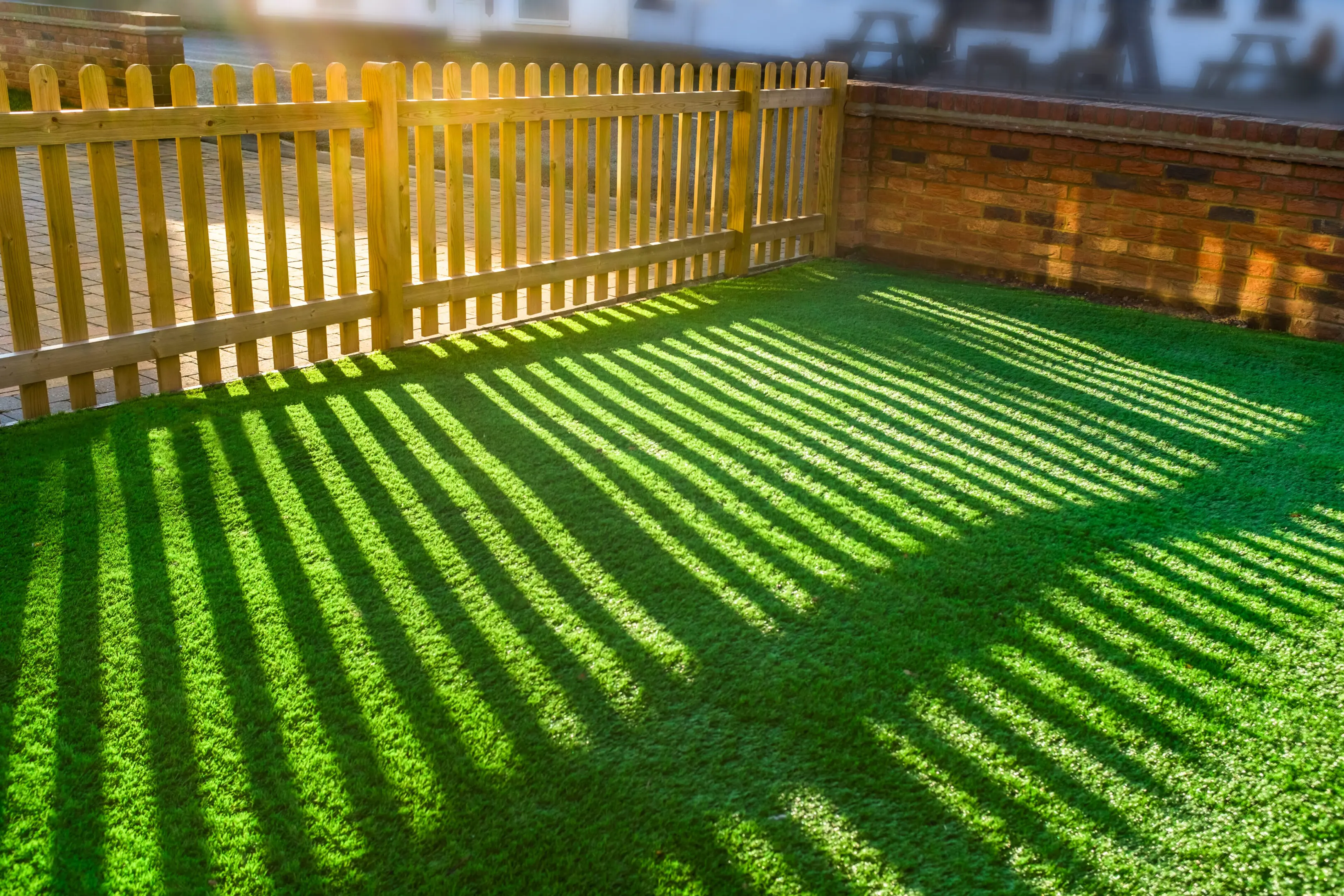 A wooden fence and grass in the sun.