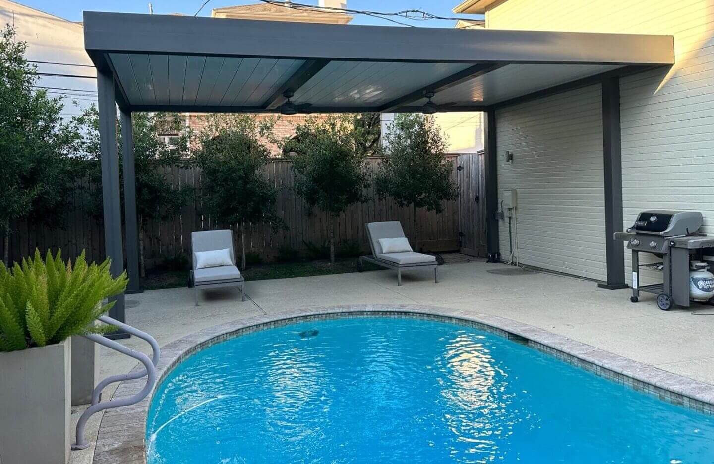 A pool with two chairs and an awning over it.
