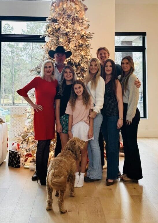 Family posing by decorated Christmas tree.